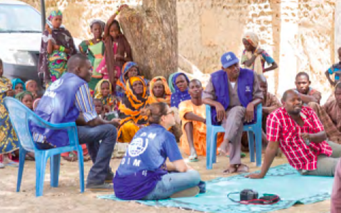 A community gather and speak with IOM staff present
